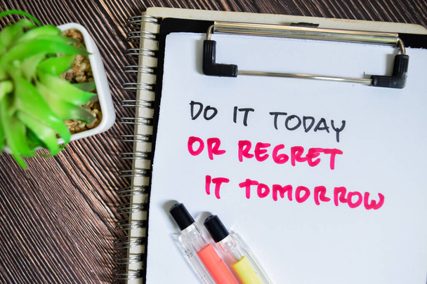 Concept of Do It Today or Regret it Tomorrow write on paperwork isolated on Wooden Table. - Photo, Image