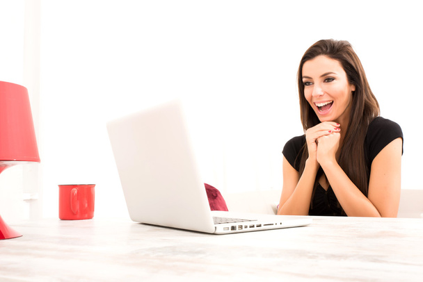 Όμορφη κοπέλα που ευτυχώς χρησιμοποιώντας ένα φορητό υπολογιστή στο σπίτι - Φωτογραφία, εικόνα
