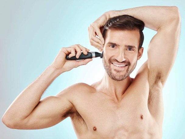 Portret mężczyzny i broda do golenia z przycinaczem w studiu odizolowanym na niebieskim tle do depilacji. Pielęgnacja włosów twarzy, uwodzenie i model męski z golarką elektryczną do golenia dla higieny i odnowy biologicznej - Zdjęcie, obraz