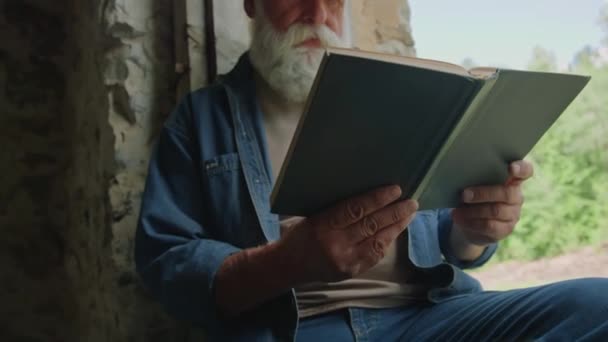 Zoom avant d'un retraité pensif lisant un livre de science-fiction assis à l'intérieur d'une maison hors réseau - Séquence, vidéo