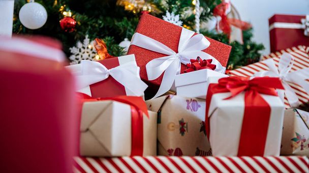 Des coffrets cadeaux soigneusement emballés sous le sapin de Noël contemporain dans une maison, complétés par des ornements de Noël de vacances, un décor festif pour le Nouvel An. - Photo, image