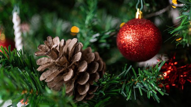 De weelderige dennenboomtakken komen tot leven met de toevoeging van een kerstdennenappel, waardoor de kerstballen en sneeuwvlokken een prachtige en feestelijke decoratie worden.. - Foto, afbeelding