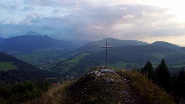 Vista aérea de uma cruz de aço cristã religiosa em uma colina na paisagem montanhosa,. Imagens 4k de alta qualidade - Filmagem, Vídeo