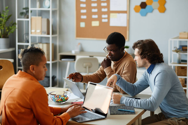 Портрет занятой бизнес-команды с ноутбуками во время совместной работы за столом заседаний в офисе - Фото, изображение