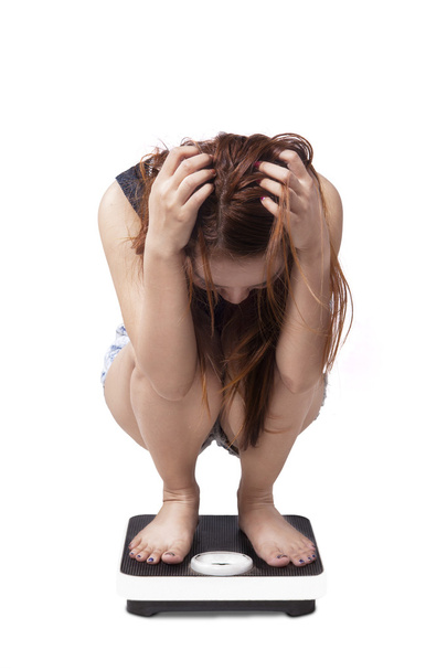 Unhappy girl squat on a weight scales - Photo, Image