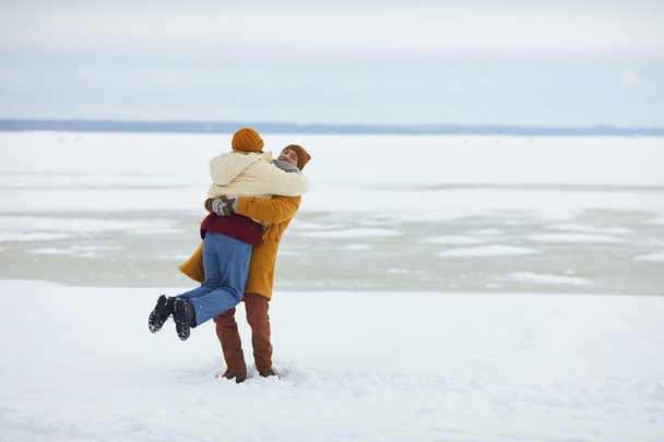 Πλήρες πορτρέτο του ανέμελου νεαρού ζευγαριού αγκαλιάζει σε ελάχιστο χειμερινό τοπίο, αντιγραφή χώρου - Φωτογραφία, εικόνα