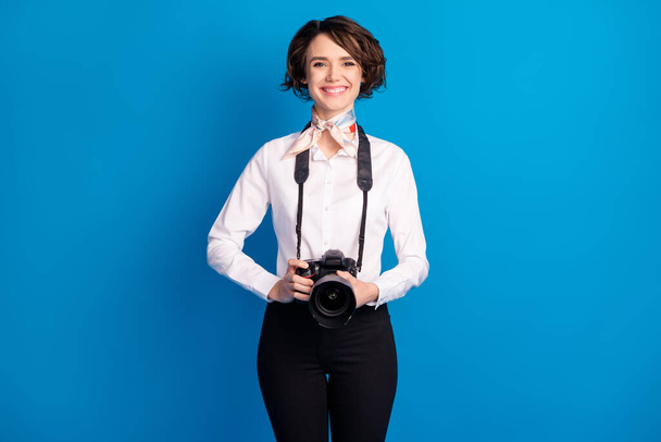 Portrait of charming satisfied lady hands hold camera toothy smile isolated on blue color background. - 写真・画像
