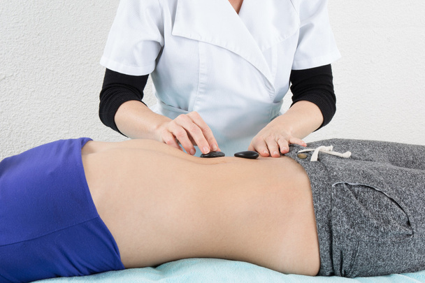 Доросла жінка має масаж гарячим каменем у спа-салоні
 - Фото, зображення