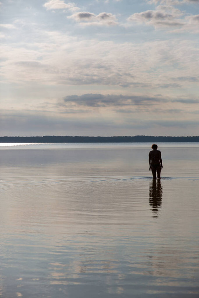 Silueta de una mujer que va a nadar en el lago durante el día - Foto, Imagen