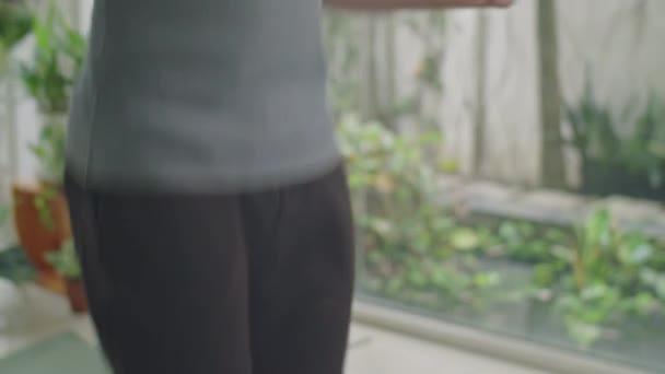 Hombre musculoso en ropa deportiva saltando cuerda en casa mientras hace ejercicio cardiovascular o se calienta - Metraje, vídeo