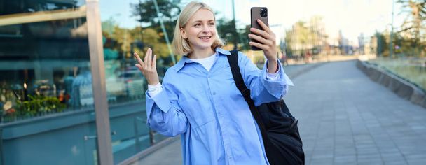 Retrato de mulher sorridente, estilo de vida blogueiro gravação de vídeo no smartphone, bate-papo on-line, olhando para a câmera móvel, falando com alguém on-line, de pé na rua. - Foto, Imagem