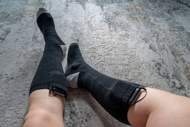 vrouw draagt batterij aangedreven verwarmde sokken voor koude winter - Foto, afbeelding