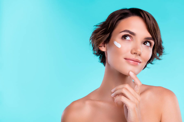 Photo of minded lady using cream thinking about smooth soft skin over aquamarine background. - Photo, Image
