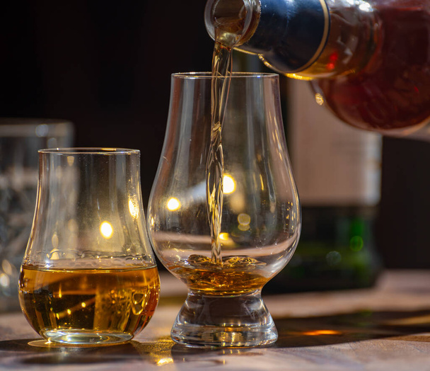 Einschenken von Whisky, Gläsern Single Malt und Blended Scotch Whisky, serviert in einer Bar in Edinburgh, Schottland, Großbritannien mit Partybeleuchtung im Hintergrund - Foto, Bild