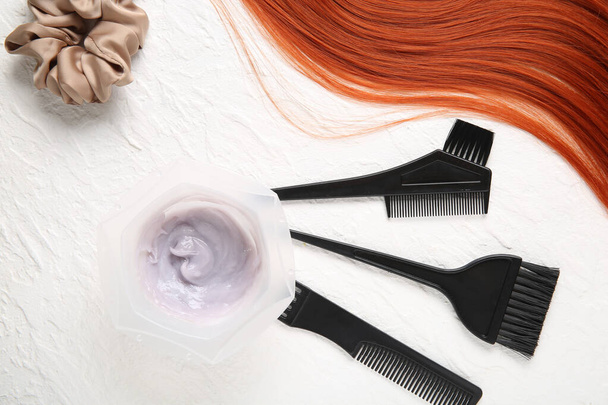 Hilo de jengibre, tazón con tinte para el cabello y conjunto de herramientas de peluquería sobre fondo blanco - Foto, imagen