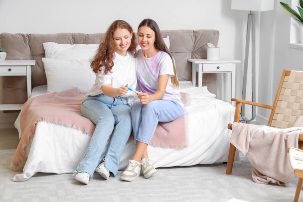 Glücklich jung lesbisch paar mit schwangerschaftstest im schlafzimmer - Foto, Bild