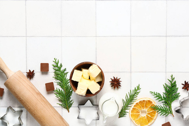 Различные ингредиенты для приготовления рождественского пирога на белом фоне плитки - Фото, изображение