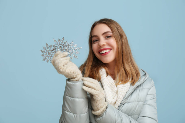 Belle jeune femme avec des flocons de neige décoratifs sur fond bleu - Photo, image