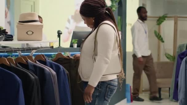 Γυναίκα πάρει διακόπτεται από φίλο, ενώ περιήγηση μέσα από προϊόντα σε κατάστημα λιτότητα με vintage ρούχα. Πελάτης έκπληκτος να ανταποκριθεί γνωριμία σε premium μεταχειρισμένο κατάστημα ενδυμάτων - Πλάνα, βίντεο