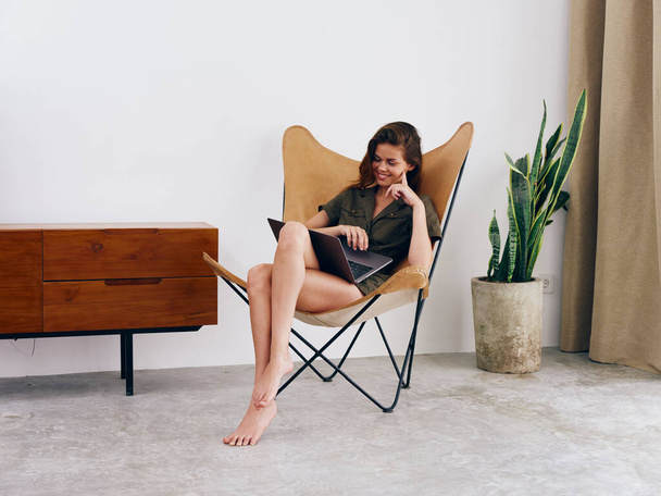 Menina estudante educação sentado em uma cadeira com um laptop trabalhar em casa sorrir e relaxar, moderno estilo de vida escandinavo interior elegante, espaço de cópia. Foto de alta qualidade - Foto, Imagem