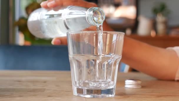 El agua que vierte de la botella en el vaso a la mesa , - Metraje, vídeo