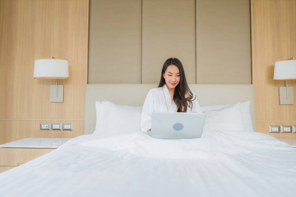 Retrato hermosa joven mujer asiática uso ordenador portátil en el interior del dormitorio
 - Foto, imagen