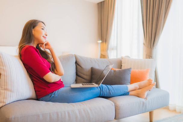 Portrét krásná mladá asijská žena použít notebook na pohovce v obývacím pokoji v ložnici interiér - Fotografie, Obrázek