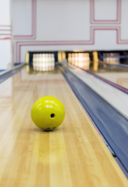 Yellow bowling ball rolling toward pins - Fotó, kép