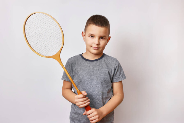 Um rapaz sorridente tem uma raquete de badminton nas mãos. Esportes e educação física. - Foto, Imagem
