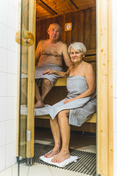 Seniorzy pocący się w saunie hotelowej podczas wakacji, pełne ujęcie pionowe. Wysokiej jakości zdjęcie - Zdjęcie, obraz
