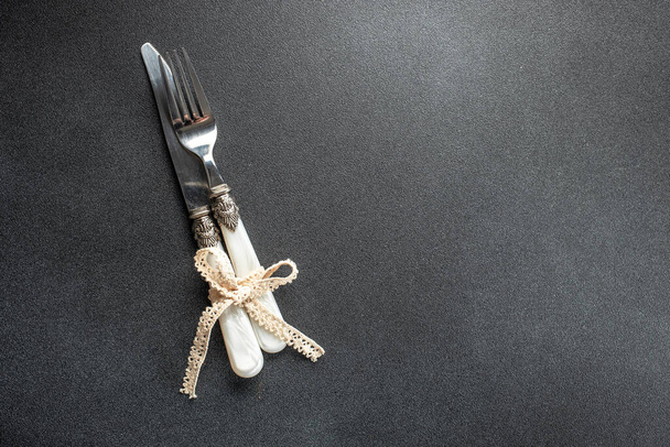 Cuchillo y tenedor atados con cuerda, mesa de ajuste de fondo oscuro. Vista superior. espacio de copia para texto, - Foto, imagen