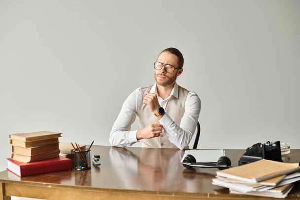 İyi görünümlü, sakallı ve gözlüklü bir adam ofiste sıkı çalışırken masada oturuyor. - Fotoğraf, Görsel