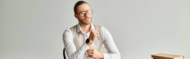 bell'uomo concentrato con barba e occhiali seduto a tavola mentre lavora sodo in ufficio, striscione - Foto, immagini