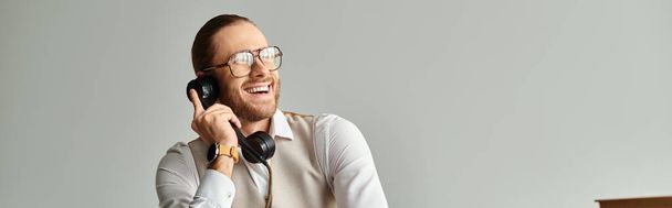 vrolijke knappe man met baard en bril praten door retro telefoon en weg te kijken, banner - Foto, afbeelding