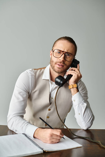 jóképű fókuszált férfi szakállal és szemüveggel beszél retro telefonnal és a kamerába néz - Fotó, kép