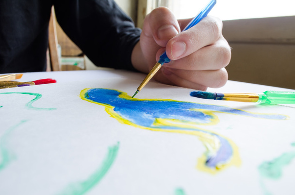 Levá ruka kreslí štětec s modrou barvou na papíře v albu s sev - Fotografie, Obrázek