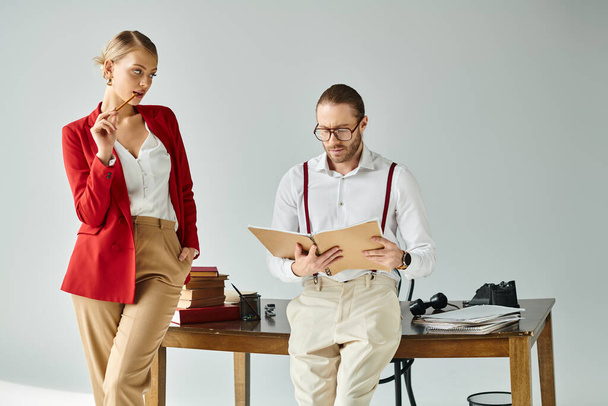 εμφανίσιμη νεαρή γυναίκα με το ζωηρό κόκκινο μπουφάν που κοιτάζει επίμονα το σκληρά εργαζόμενο αφεντικό της. - Φωτογραφία, εικόνα