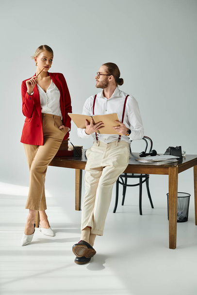 hete blonde vrouw in rode jas op zoek verleidelijk naar haar sexy baas met baard, werk affaire - Foto, afbeelding