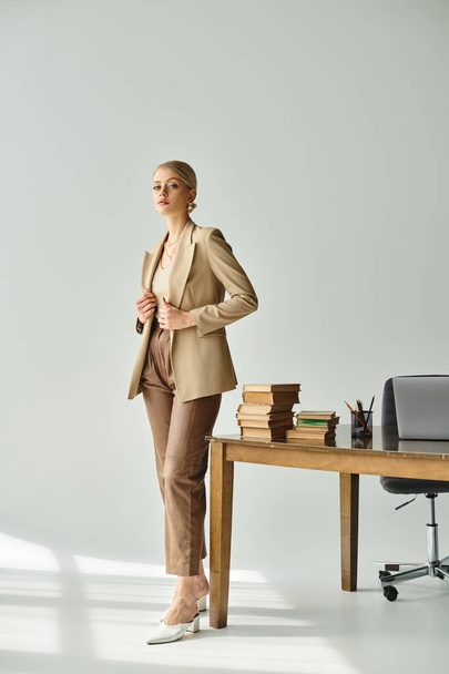 krásná mladá žena s blond vlasy v elegantním obleku a při pohledu na kameru v kanceláři - Fotografie, Obrázek
