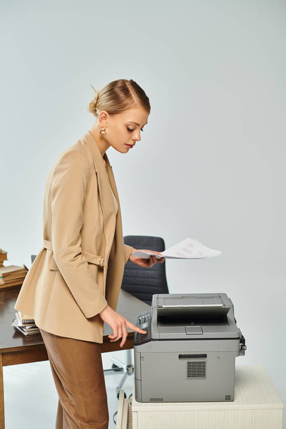 atrakcyjna młoda kobieta z zebranymi blond włosami przy użyciu kopiarki podczas pracy w biurze - Zdjęcie, obraz