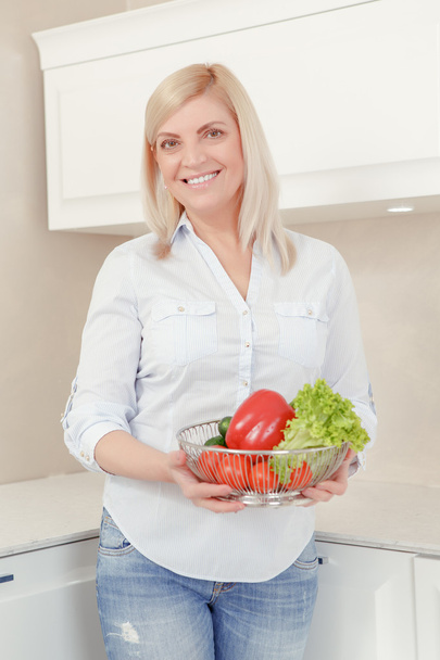 Woman holds a plate with vegetables - Zdjęcie, obraz