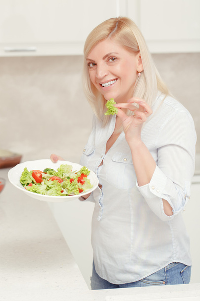 Woman cooks salad in the kitchen - Foto, afbeelding