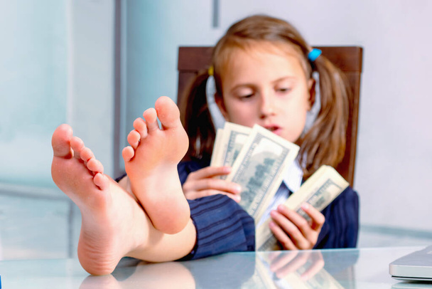 Portrait of happy young girl counts money profit. Selective focus on bare feet - Photo, Image