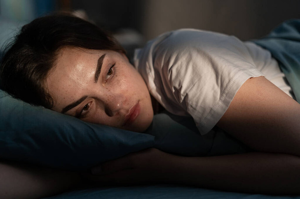 Zaburzenia snu, bezsenność. Młoda kobieta leżąca na łóżku, obudzona późną nocą. Nie mogę spać. Przestrzeń kopiowania - Zdjęcie, obraz
