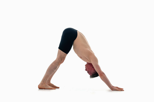 muž ve sportovním oblečení dělá jógu cvičení na bílém pozadí. Adho Mukha vansana. Směrem dolů psí pode, Ashtanga jóga  - Fotografie, Obrázek
