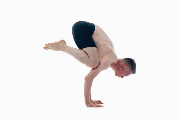 Bakasana ( Crane pose), Ashtanga yoga  Side view of man wearing sportswear doing Yoga exercise against white background.  - Photo, Image