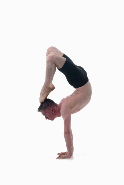 Врищасана (Поза Скорпиона), йога Аштанга Вид сбоку на человека, одетого в йогу, на белом фоне.  - Фото, изображение