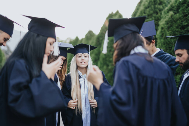 University students, in graduation attire, celebrate their achievement in a park. Standing in a circle, they share positive memories, smiles, and congratulations, creating lasting friendships. - Photo, Image