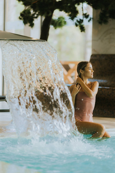 Ładna młoda kobieta relaksująca się przy krytym basenie - Zdjęcie, obraz