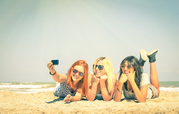 Счастливые подруги, делающие селфи на пляже - Очаг дружбы и веселья летом с новыми тенденциями и технологиями - Лучшие друзья, наслаждающиеся моментами с помощью современного смартфона - Винтажный отфильтрованный взгляд
 - Фото, изображение